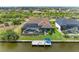 Aerial view of a backyard with a screened pool, waterfront access, and a private dock with seating and an umbrella at 8304 Antwerp Cir, Port Charlotte, FL 33981
