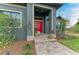Close up of the front entrance showcasing a red door, stone walkway, manicured landscaping, and inviting curb appeal at 8304 Antwerp Cir, Port Charlotte, FL 33981