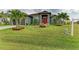 Home exterior showcasing a verdant lawn, mature palm trees, and tasteful landscaping, enhancing its curb appeal and serene setting at 8304 Antwerp Cir, Port Charlotte, FL 33981