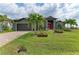 Home exterior with a lush green lawn adorned with palm trees and decorative planters, creating a welcoming and well-maintained entrance at 8304 Antwerp Cir, Port Charlotte, FL 33981
