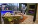 Stylish outdoor living area with a cozy fireplace, plush seating, and a view of the inviting pool and lush greenery at 8304 Antwerp Cir, Port Charlotte, FL 33981