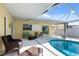 A screened pool and patio with wicker seating and tropical cushions are perfect for relaxing and enjoying the outdoors at 840 Park Rd, Englewood, FL 34223
