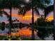 Beautiful canal view with palm trees against a backdrop of a vibrant sunset at 9325 Saint Paul Dr, Port Charlotte, FL 33981