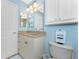 Bright bathroom with a vanity with decorative pulls, an overhead cabinet and a separate toilet at 9325 Saint Paul Dr, Port Charlotte, FL 33981