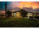 Charming home exterior featuring a well-manicured lawn, mature palms, and warm, inviting outdoor lighting at sunset at 9325 Saint Paul Dr, Port Charlotte, FL 33981