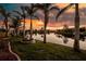 Picturesque waterfront view showcases palm trees, a decorative fountain, and calm waters reflecting a vibrant sunset at 9325 Saint Paul Dr, Port Charlotte, FL 33981