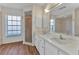 Bathroom with double sinks, shower, bathtub, wood-look floors, and a large window for natural light at 977 N Doral Ln, Venice, FL 34293
