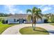 Beautiful home featuring lush landscaping, an elegant entryway, and a circular driveway with palm tree at 977 N Doral Ln, Venice, FL 34293