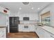 Updated kitchen with stainless refrigerator, white cabinets, modern appliances, wood-look flooring, and a view to the pool at 977 N Doral Ln, Venice, FL 34293