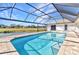 View of screened pool and the beautiful landscaping behind the home at 977 N Doral Ln, Venice, FL 34293