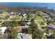An aerial view of a charming home with a lush green yard surrounded by trees and a glimpse of a sparkling waterway at 1104 Larchmont Dr, Englewood, FL 34223
