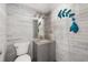 Stylish half-bathroom with light wood plank walls, modern vanity, and decorative fish wall art at 1104 Larchmont Dr, Englewood, FL 34223