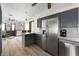 Modern kitchen with stainless steel appliances, gray cabinets, and a breakfast bar, adjacent to living room at 1104 Larchmont Dr, Englewood, FL 34223