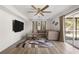 Bright living room features a modern ceiling fan, stylish rug, and sliding glass doors to a patio area at 1104 Larchmont Dr, Englewood, FL 34223