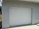 A single car garage with a white garage door at 11090 Mcfadden Ave, Englewood, FL 34224