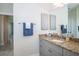 Bathroom featuring granite counters, grey cabinets, blue accents, decorative mirror, and tile flooring at 13252 Keystone Blvd, Port Charlotte, FL 33981