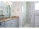 Bathroom with granite counters, grey cabinets, dual mirror, and walk-in shower with natural stone tile at 13252 Keystone Blvd, Port Charlotte, FL 33981