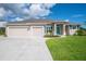Charming home featuring a three-car garage, well-manicured lawn, and a welcoming bright blue front door at 13252 Keystone Blvd, Port Charlotte, FL 33981