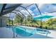 Screened-in pool with a blue umbrella, surrounded by lush greenery at 13252 Keystone Blvd, Port Charlotte, FL 33981