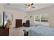 Bright bedroom featuring a ceiling fan, dresser, and large window with backyard views at 15613 Alsask Cir, Port Charlotte, FL 33981