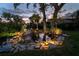 Scenic backyard with a tranquil pond, rock features, and lush landscaping with ambient lighting at 1648 Shelburne Ln, Sarasota, FL 34231