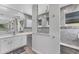 Modern bathroom with a large mirror, white cabinets, countertops, and gray-tiled shower with frameless glass at 18610 Ayrshire, Port Charlotte, FL 33981