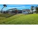 Expansive backyard featuring a screened lanai, lush lawn, and mature landscaping providing privacy at 202 South Dr, Englewood, FL 34223