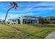 Backyard view of the home highlighting the screened-in lanai and spacious yard with mature landscaping at 202 South Dr, Englewood, FL 34223