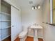 Bathroom with pedestal sink, toilet, shelving unit, and window with natural light at 202 South Dr, Englewood, FL 34223