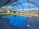 Sparkling pool in screened lanai with brick pavers, overlooking lush tropical landscaping and waterfront views at 202 South Dr, Englewood, FL 34223
