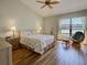 Bright bedroom with hardwood floors, ceiling fan, and large window overlooking the lake at 220 Southampton Drive # 325, Venice, FL 34293