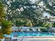 Community pool with lounge chairs and tables, surrounded by mature trees and a white fence at 220 Southampton Drive # 325, Venice, FL 34293