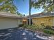 A charming yellow house features a two-car garage, mature shrubs, and an inviting, shaded entrance at 220 Southampton Drive # 325, Venice, FL 34293