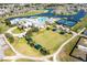 Aerial view of a community clubhouse, pool, tennis courts, and lawn bowling set in a golf community at 24135 Buckingham Way, Punta Gorda, FL 33980