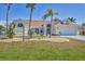 Charming single-Gathering home featuring a well-manicured lawn and tropical landscaping including palm trees at 2418 Herron Ter, Port Charlotte, FL 33981