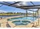 Beautiful pool and spa with clear water, surrounded by a screened enclosure offering privacy and a waterfront view at 2418 Herron Ter, Port Charlotte, FL 33981