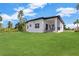 Spacious backyard featuring lush green lawn, covered patio, and modern architecture at 280 Antis Dr, Rotonda West, FL 33947
