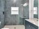 Modern bathroom with a rain shower head, blue tiled shower, and granite countertop at 280 Antis Dr, Rotonda West, FL 33947