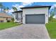 Beautiful home with a gray garage door, modern landscaping, and a paver driveway at 280 Antis Dr, Rotonda West, FL 33947