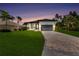 Beautiful single-Gathering home featuring a manicured lawn and brick paver driveway under a gorgeous sunset sky at 280 Antis Dr, Rotonda West, FL 33947