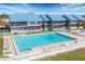 Aerial view of community pool with blue apartment buildings and lounge chairs surrounding the pool at 4410 Warren Ave # 217, Port Charlotte, FL 33953