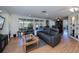 Open-concept living room with hardwood floors, a stylish gray couch and expansive sliding doors for natural light at 62 Oakland Hills Pl, Rotonda West, FL 33947