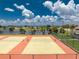 Close-up aerial view of the community tennis courts and lake, surrounded by lush landscaping and clear blue skies at 6375 Coniston St, Port Charlotte, FL 33981