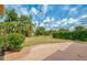 Spacious backyard featuring mature trees, manicured landscaping, and a concrete patio at 7215 Brookhaven Ter, Englewood, FL 34224