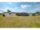 Expansive backyard featuring a large lawn, screened enclosure, and storage shed on a sunny day at 7215 Brookhaven Ter, Englewood, FL 34224