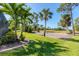 Well-manicured backyard with lush green grass and mature trees leads to a golf course at 758 Rotonda Cir, Rotonda West, FL 33947