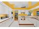 Bright kitchen with white cabinets, wood trim, yellow accents, and an island at 850 Van Gogh Road, Englewood, FL 34223