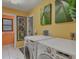 Bright laundry room featuring front loading washer and dryer, tile floors, and beach themed artwork at 850 Van Gogh Road, Englewood, FL 34223