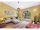 Comfortable living room with a plush sectional sofa and sun-filled arched window at 850 Van Gogh Road, Englewood, FL 34223