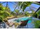 Screened-in pool area with lounge chairs and lush tropical landscaping at 850 Van Gogh Road, Englewood, FL 34223